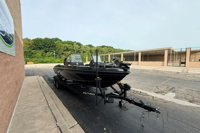 Slide: The Image of 2024 Nitro ZV20 boat on trailer in parking lot, surrounded by trees and buildings. - 12