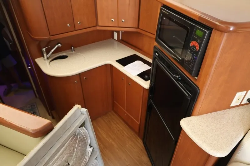 Slide: The Image of 2005 Silverton 34 Convertible yacht kitchen with wood cabinetry, sink, microwave, and refrigerator. - 15
