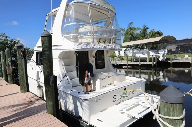 Slide: The Image of 2005 Silverton 34 Convertible yacht docked at marina, featuring spacious deck and clear skies. - 17