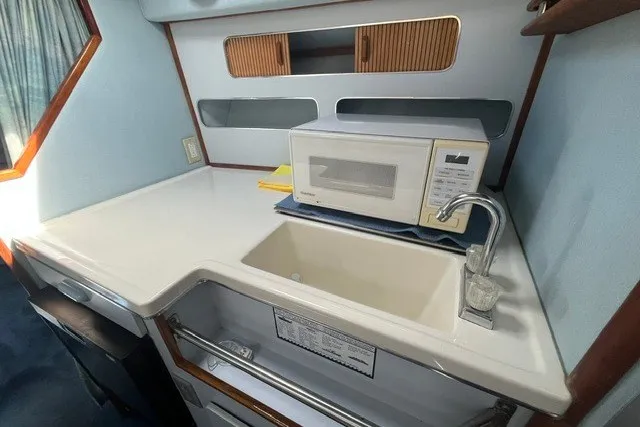 Slide: The Image of 1989 Sea Ray 300 Weekender galley with sink, microwave, and storage cabinets. - 23
