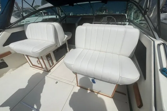 Slide: The Image of 1989 Sea Ray 300 Weekender boat interior with white cushioned seating and steering area. - 4