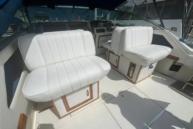 Slide: The Image of 1989 Sea Ray 300 Weekender boat interior with white cushioned seating and steering console. - 6