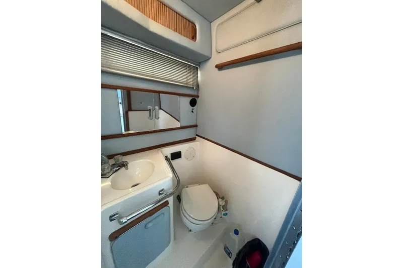 Slide: The Image of 1989 Sea Ray 300 Weekender boat bathroom with sink, toilet, and mirror. - 28