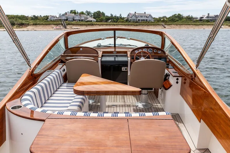 Slide: The Image of 2025 Hinckley Yachts Talaria 29 Runabout interior with elegant wood finish and striped seating. - 13