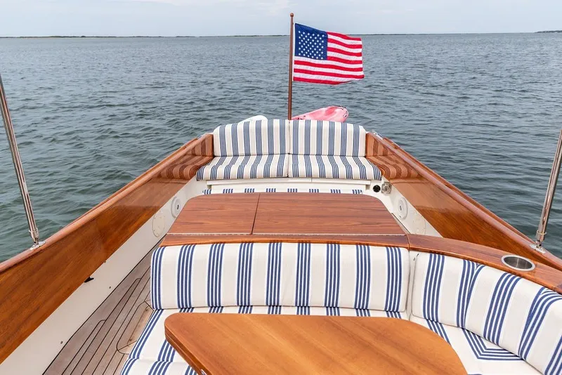 Slide: The Image of 2025 Hinckley Yachts Talaria 29 Runabout with striped seating and American flag on open water. - 2