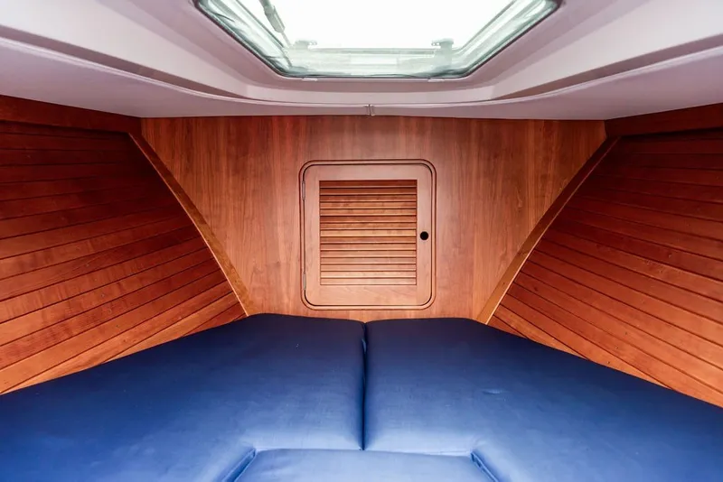 Slide: The Image of Interior cabin of 2025 Hinckley Yachts Talaria 29 Runabout with wood paneling and blue cushions. - 20