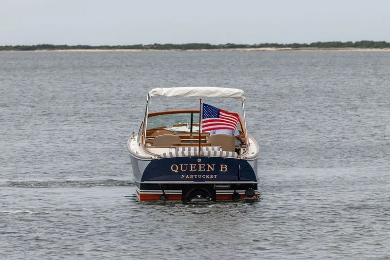 Slide: The Image of 2025 Hinckley Yachts Talaria 29 Runabout on water, American flag, "Queen B" name visible. - 35