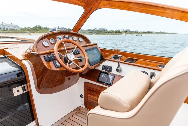 Slide: The Image of 2025 Hinckley Yachts Talaria 29 Runabout helm with wooden dashboard and leather seating. - 7