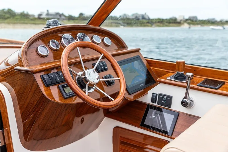 Slide: The Image of 2025 Hinckley Yachts Talaria 29 Runabout dashboard with wooden steering wheel and modern controls. - 3