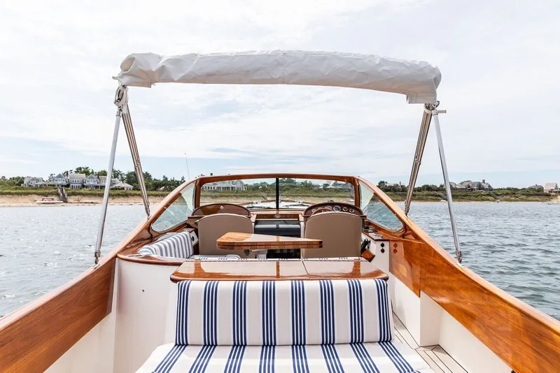 Slide: The Image of 2025 Hinckley Yachts Talaria 29 Runabout with elegant wood finish and striped seating. - 16