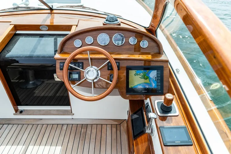 Slide: The Image of 2025 Hinckley Yachts Talaria 29 Runabout dashboard with wooden steering wheel and navigation display. - 6