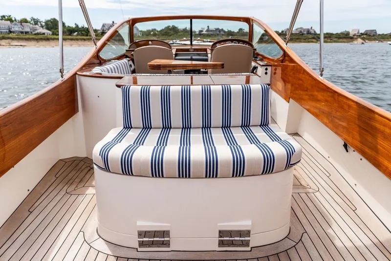 Slide: The Image of 2025 Hinckley Yachts Talaria 29 Runabout with striped seating, elegant wood finish, and scenic water view. - 17
