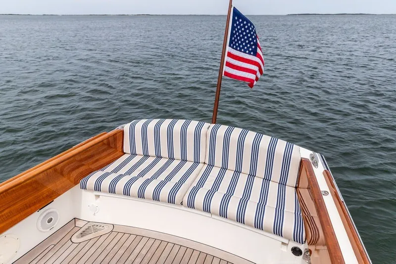 Slide: The Image of 2025 Hinckley Yachts Talaria 29 Runabout with striped seating and American flag on open water. - 19