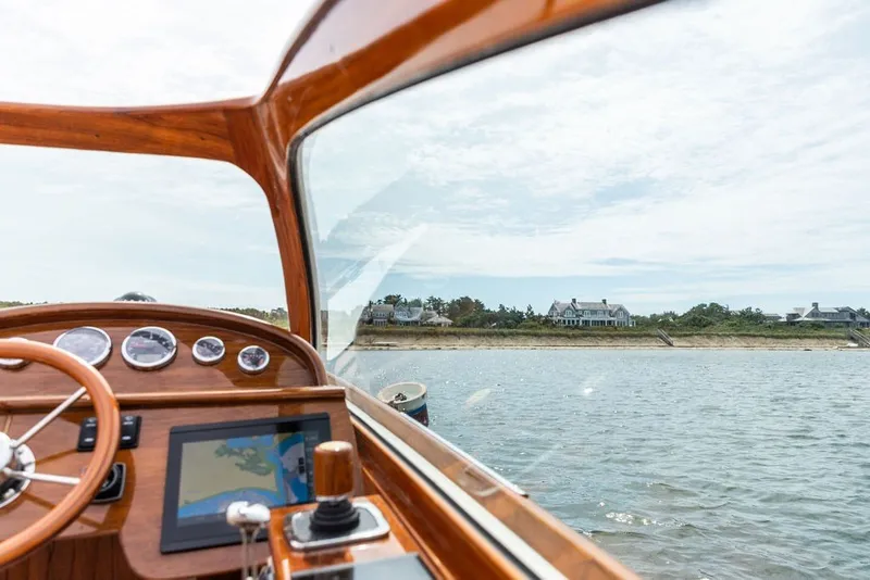 Slide: The Image of Interior view of 2025 Hinckley Yachts Talaria 29 Runabout, showcasing dashboard and scenic waterfront. - 8