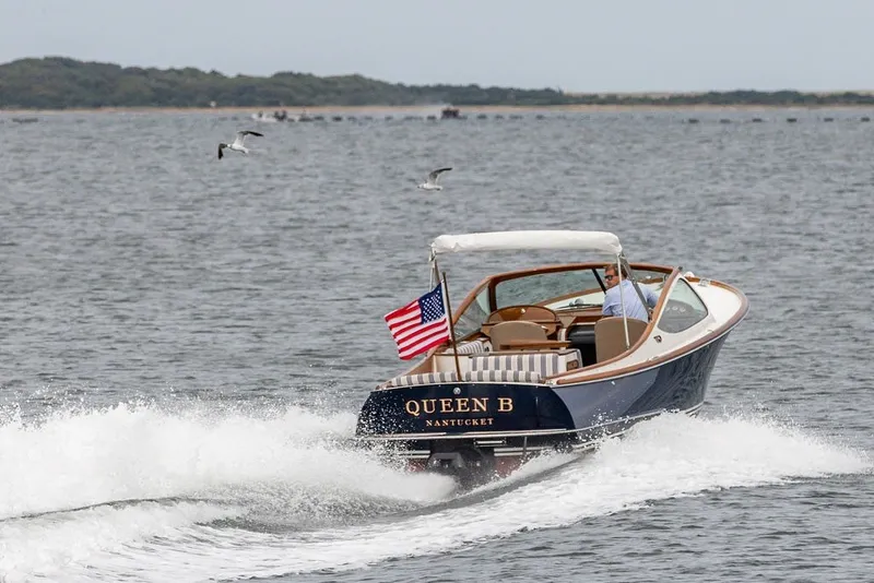 Slide: The Image of 2025 Hinckley Yachts Talaria 29 Runabout cruising on water with American flag. - 34