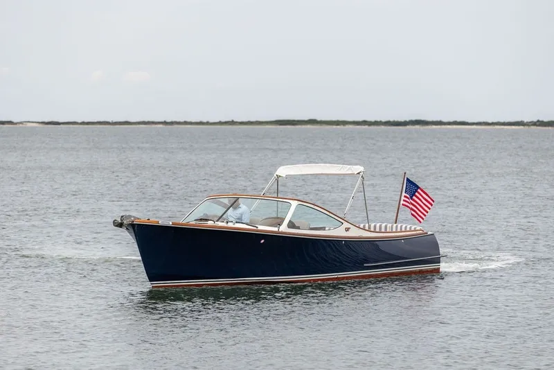 Slide: The Image of 2025 Hinckley Yachts Talaria 29 Runabout cruising on open water with American flag. - 29