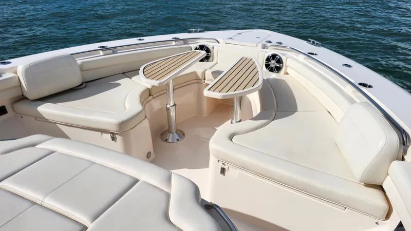 Slide: The Image of The image shows the bow area of a Grady-White Canyon 456 boat with beige cushions and wooden tables. - 20