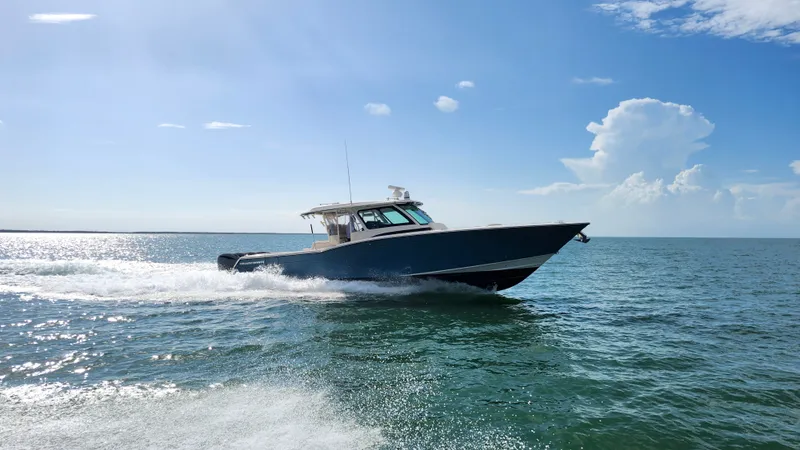 Slide: The Image of 2022 Grady-White Canyon 456 cruising swiftly on open water under a blue sky. - 2