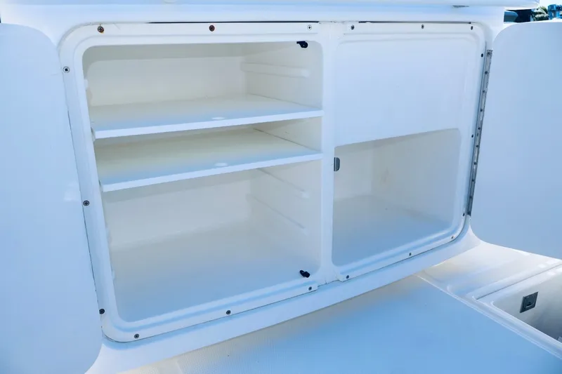 Slide: The Image of Open storage compartment on a 2010 Deep Impact 330 C boat, featuring shelves and a door. - 45