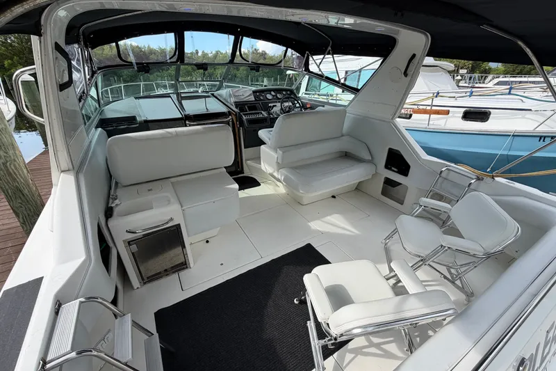 Slide: The Image of 1993 Sea Ray 400 Express Cruiser interior with white seating and helm station. - 8