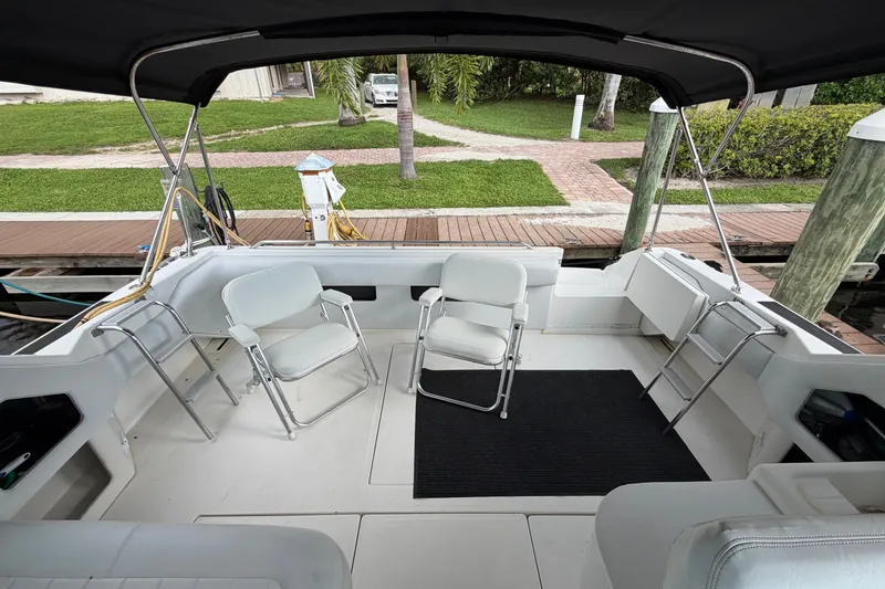 Slide: The Image of 1993 Sea Ray 400 Express Cruiser cockpit with chairs, docked by a wooden pier. - 9