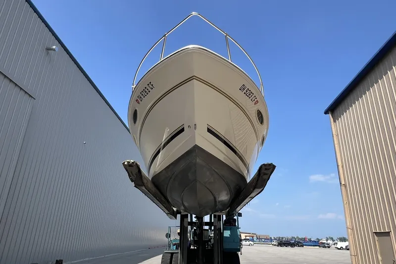 Slide: The Image of 1997 Sea Ray 240 Overnighter boat lifted at marina, clear blue sky background. - 86