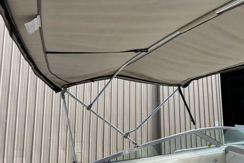 Slide: The Image of 1997 Sea Ray 240 Overnighter boat canopy with metal frame, docked near a corrugated wall. - 20
