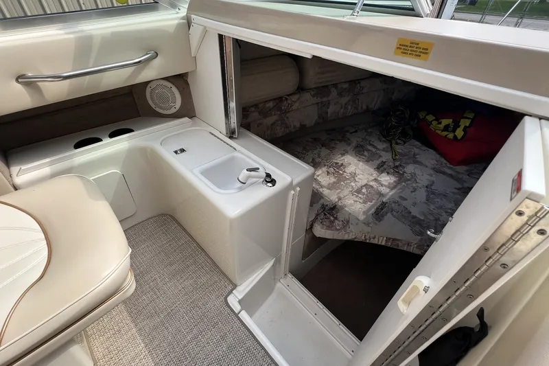 Slide: The Image of 1997 Sea Ray 240 Overnighter cabin interior with seating, sink, and sleeping area. - 45