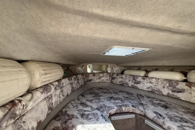 Slide: The Image of Interior cabin of a 1997 Sea Ray 240 Overnighter boat, featuring cushioned seating and storage. - 62