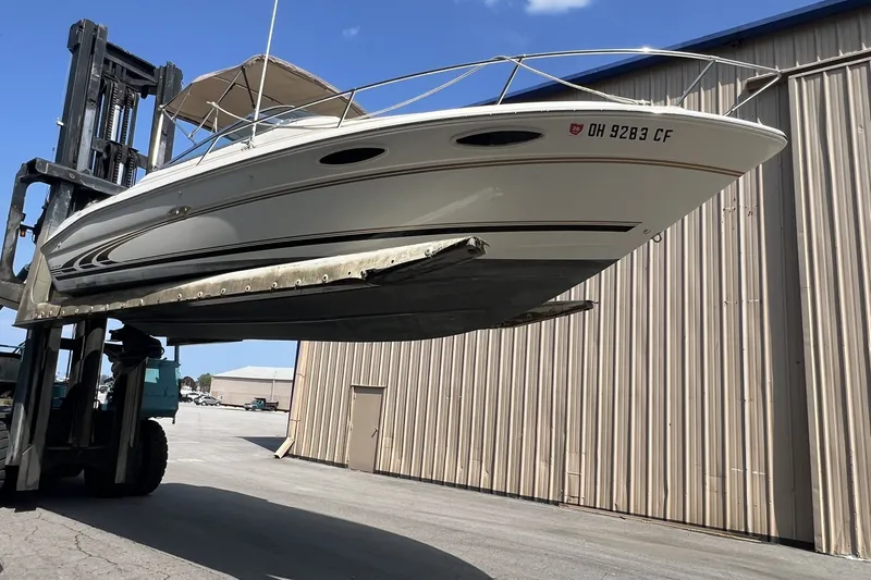 Slide: The Image of 1997 Sea Ray 240 Overnighter boat lifted by forklift near warehouse. - 87