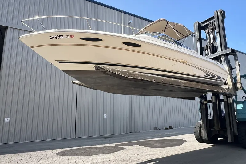 Slide: The Image of 1997 Sea Ray 240 Overnighter boat lifted by forklift near industrial building. - 85