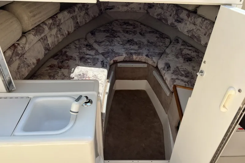Slide: The Image of 1997 Sea Ray 240 Overnighter cabin interior with sink and cushioned seating area. - 50