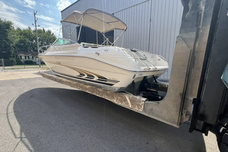 Slide: The Image of 1997 Sea Ray 240 Overnighter boat on a lift, near a building. - 84