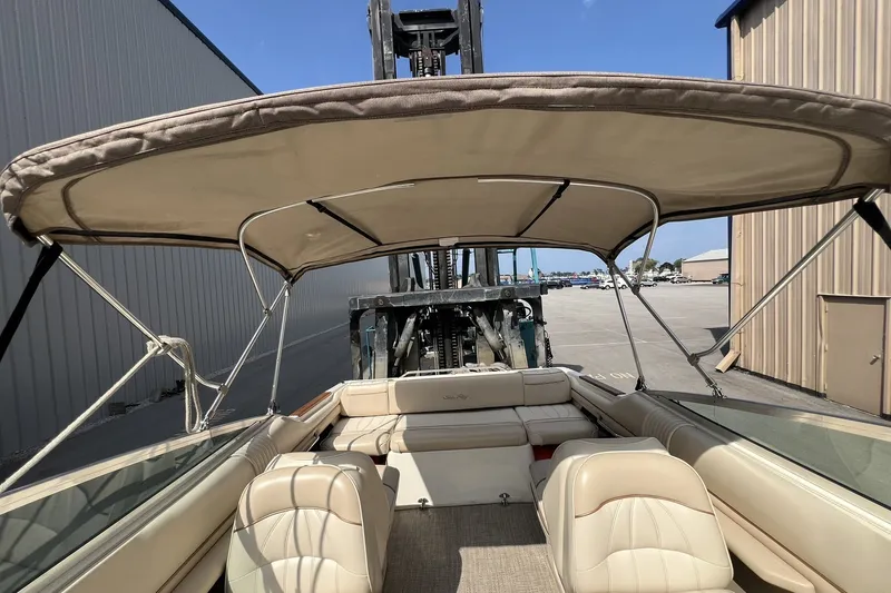 Slide: The Image of 1997 Sea Ray 240 Overnighter boat interior with beige seating and canopy, parked outdoors. - 36