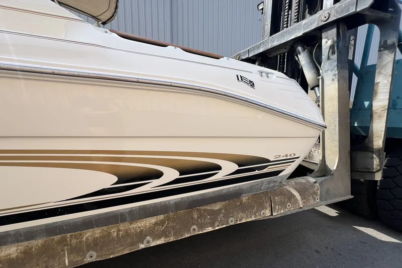 Slide: The Image of 1997 Sea Ray 240 Overnighter boat on a lift, showcasing sleek design and graphics. - 82