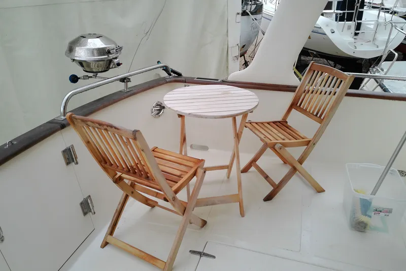 Slide: The Image of Deck of 2005 Mariner 34 Orient with wooden chairs and table, featuring a grill. - 44