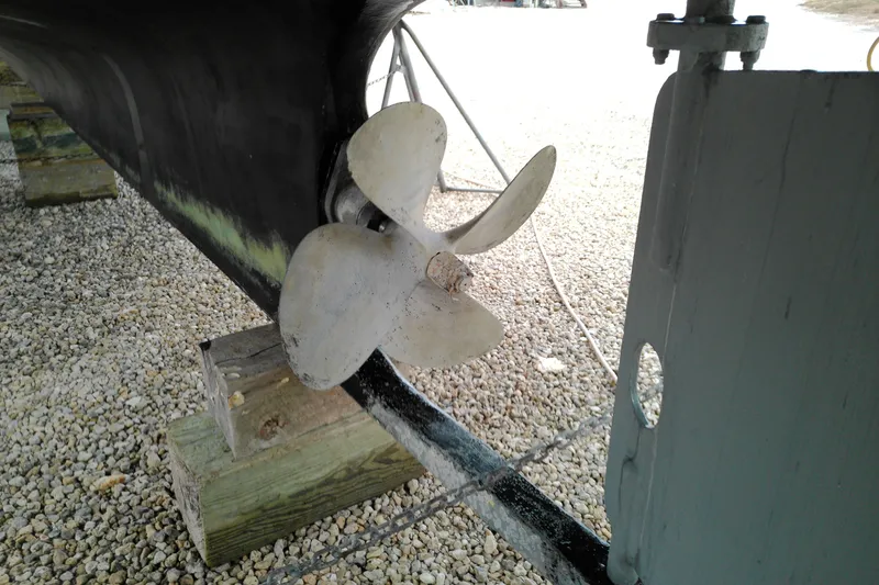 Slide: The Image of Propeller of 2005 Mariner 34 Orient boat on gravel, supported by wooden blocks. - 10