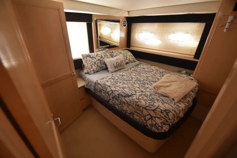 Slide: The Image of The cabin of the 2000 Carver 356 Aft Cabin Motor Yacht features a cozy bed with nautical-themed bedding. - 13