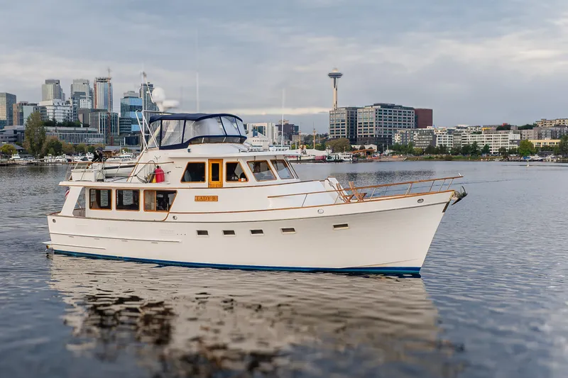 Slide: The Image of 1992 Ocean Alexander 50 Mark I yacht on calm water with city skyline backdrop. - 38