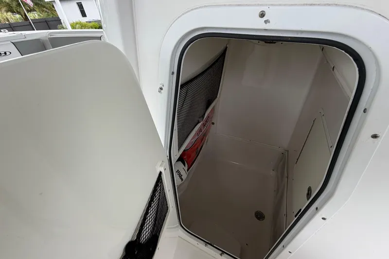 Slide: The Image of 2016 Sea Hunt Gamefish 25 storage compartment with open door, showcasing interior space. - 24