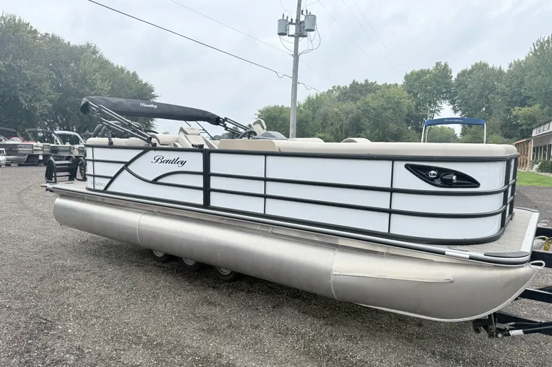 The Image of 2027 Bentley Pontoons Legacy 223 Navigator, white pontoon boat on gravel lot, overcast sky. - 0