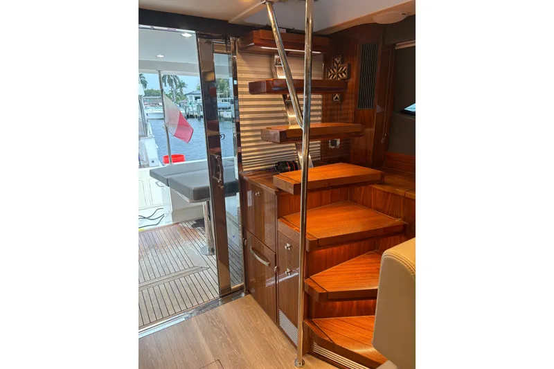 Slide: The Image of Interior of 2025 Riviera 46 Sports Motor Yacht with wooden stairs and sleek design. - 11