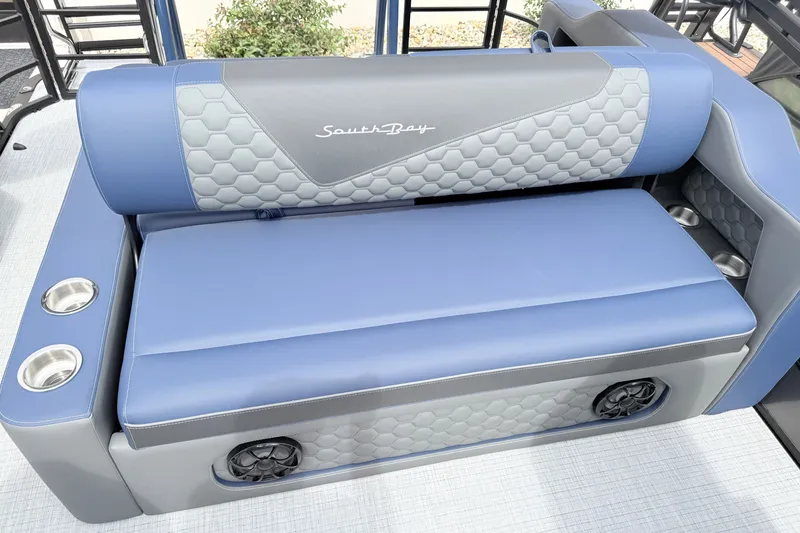 Slide: The Image of Luxurious seating on 2026 South Bay 525UL DC boat, featuring blue and gray upholstery with cup holders. - 24