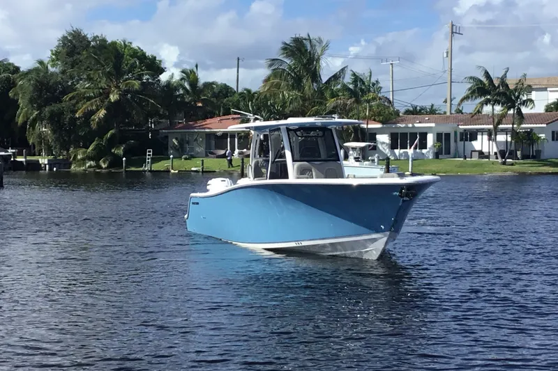 Slide: The Image of 2025 Sportsman Open 322 Center Console boat on a calm waterway, surrounded by palm trees. - 5