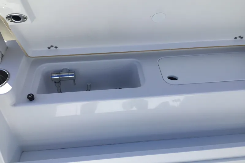Slide: The Image of 2025 Sportsman Open 322 Center Console boat storage compartment with open lid and plumbing. - 59