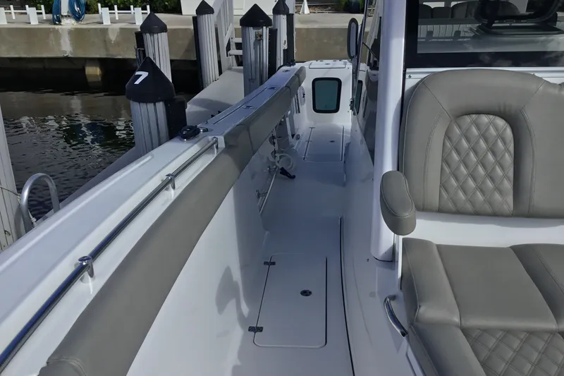Slide: The Image of 2025 Sportsman Open 322 Center Console boat interior with gray seating and dock view. - 26