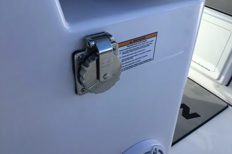 Slide: The Image of 2025 Sportsman Open 322 Center Console boat electrical outlet with safety warning label. - 68