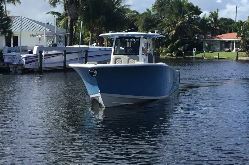 Slide: The Image of 2025 Sportsman Open 322 Center Console boat on a calm waterway, surrounded by palm trees. - 12
