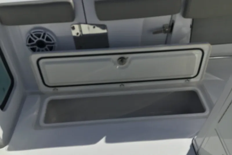 Slide: The Image of 2025 Sportsman Open 322 Center Console storage compartment with speaker and latch. - 56