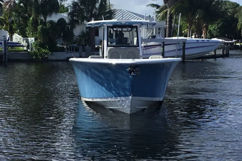 Slide: The Image of 2025 Sportsman Open 322 Center Console boat on calm water, surrounded by lush greenery. - 13